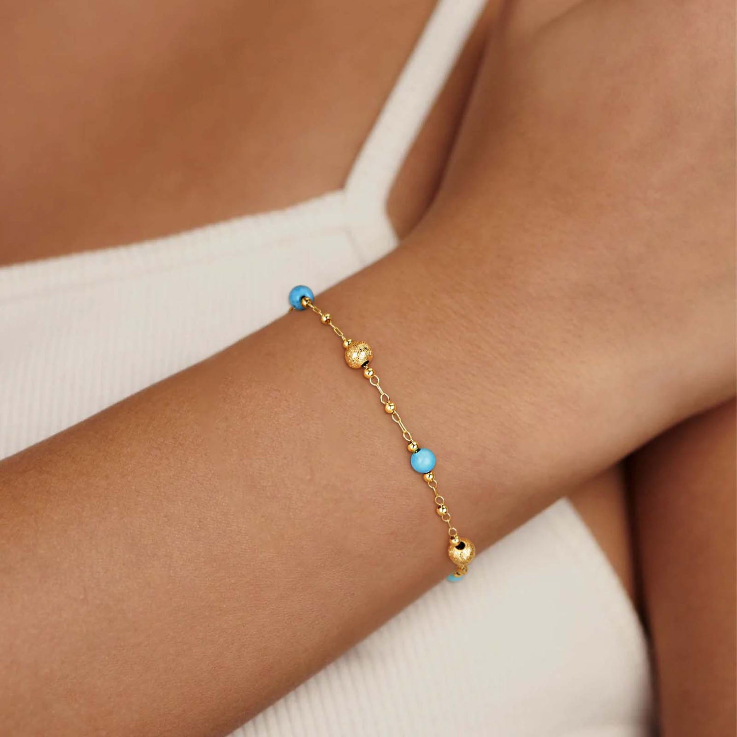 Close-up of a model wearing MYEARS® turquoise charm chain bracelet with 14K gold details, stylish turquoise jewelry for women.