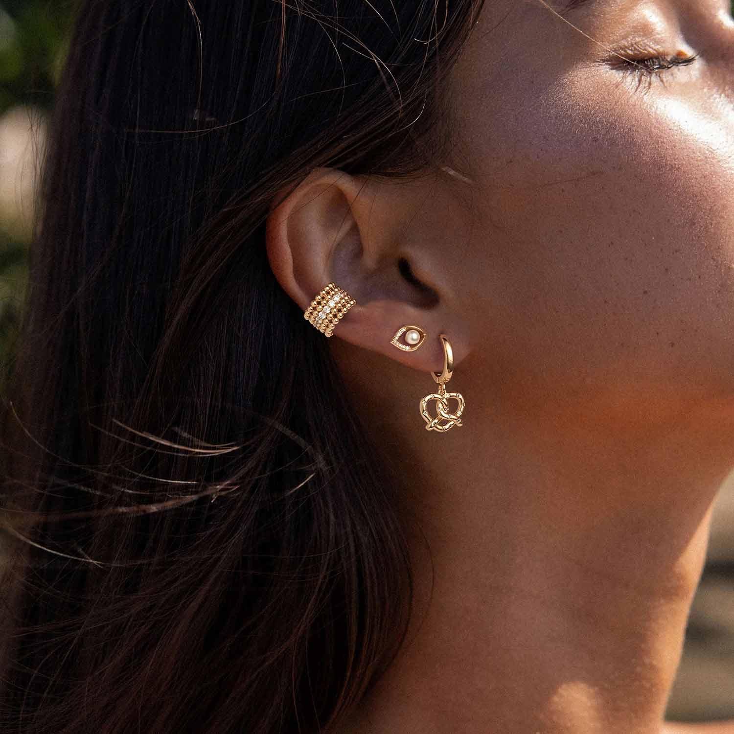 Model wearing MYEARS® evil eye pearl stud earrings, stylish everyday pearl stud earrings with evil eye charm for women.