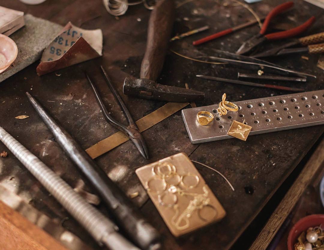 Behind the scenes at the MYERAS® studio: the focused hands of a craftsperson bringing a jewelry design to life at a well-equipped worktable