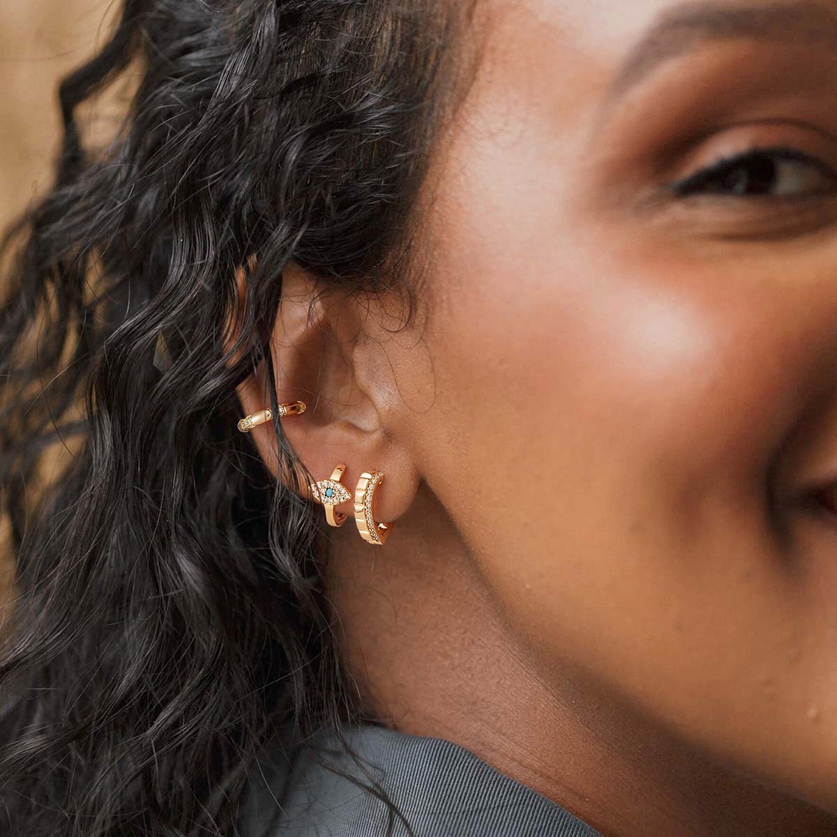 Close-up of MYEARS® Evil Eye Hoop Earrings in gold on model, showcasing detailed evil eye design and polished finish