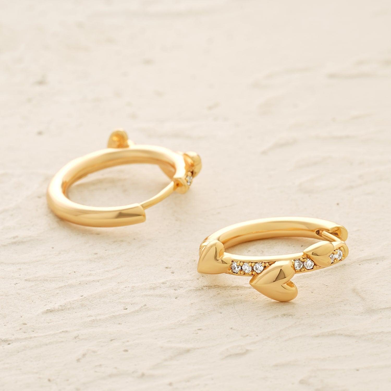 Close-up detail of MYEARS Triple Heart Huggie Earrings showing triple heart design in gold