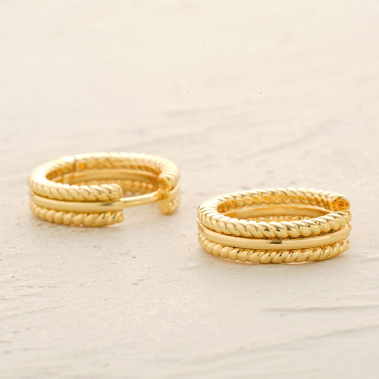 Detail of twisted band huggie hoop earrings showing twisted texture and gold finish