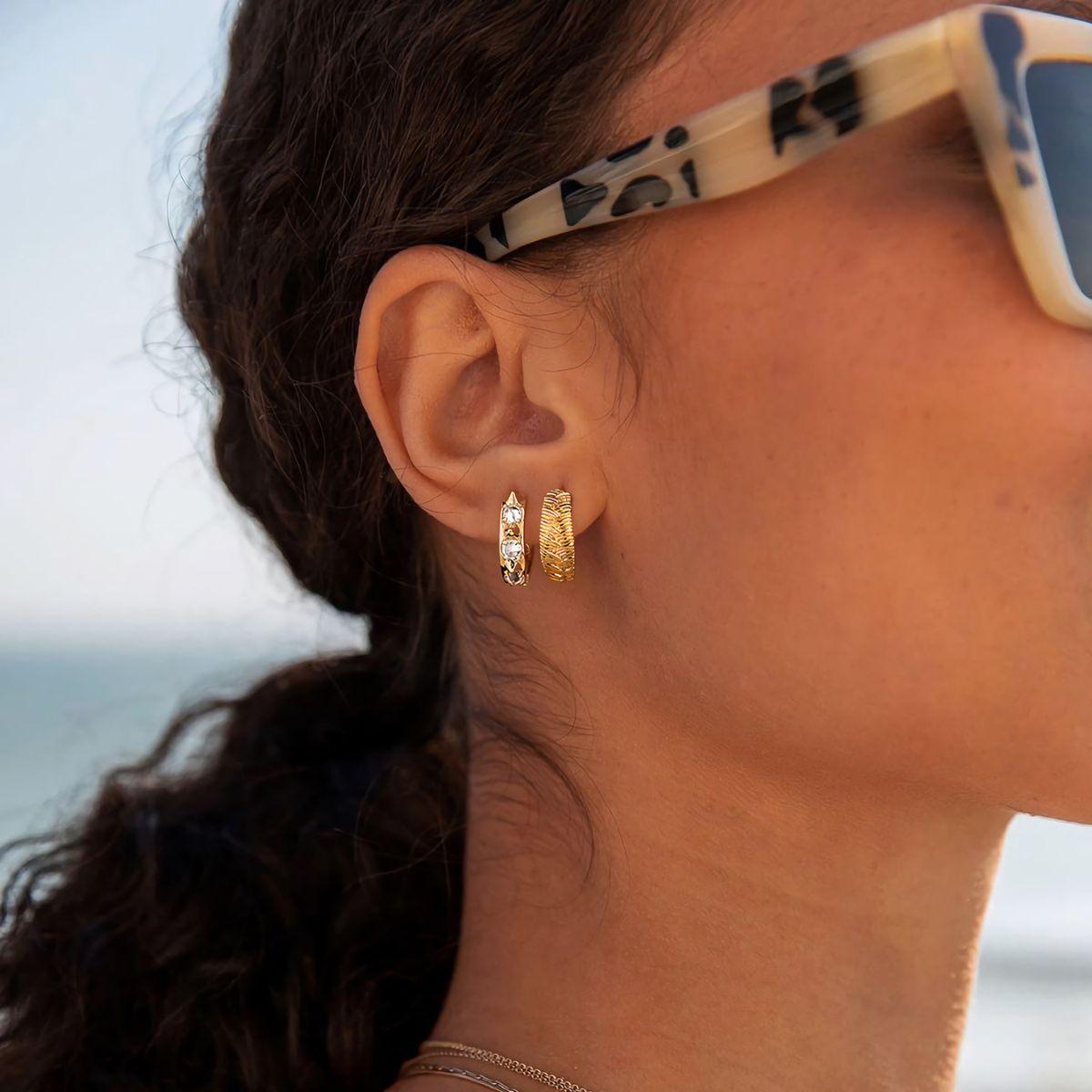 Close-up of MYEARS® gold braid hoop earrings worn by a woman, showing intricate braided design and polished finish