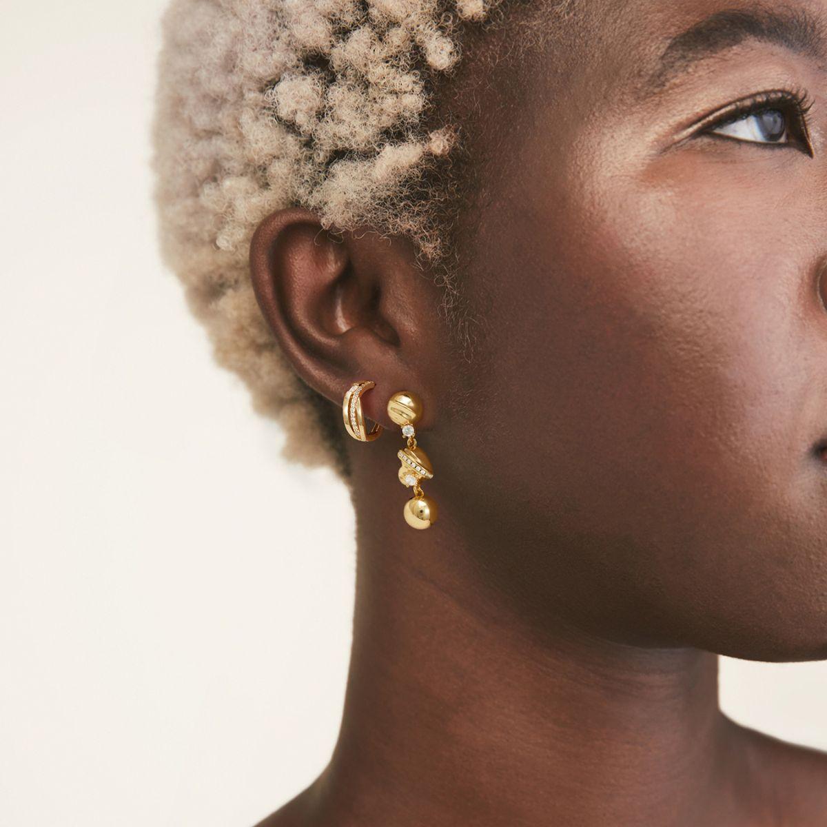 Close-up of MYEARS® CZ Split Crossover Huggie Hoop Earrings worn by a woman, showing sparkling cubic zirconia and crossover design in gold