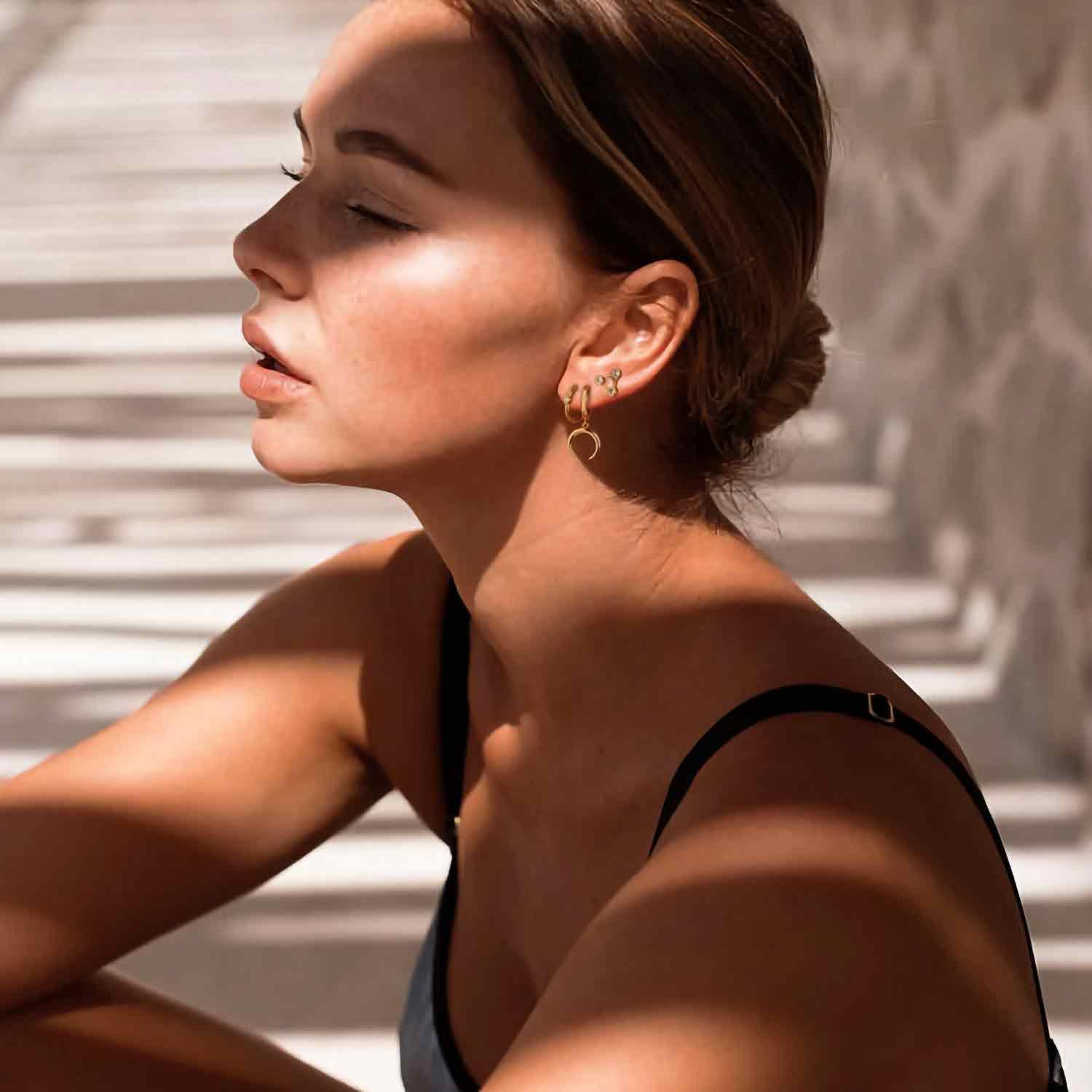 Close-up of model wearing MYEARS mini triangle CZ stud earrings, showcasing elegant gold design for women