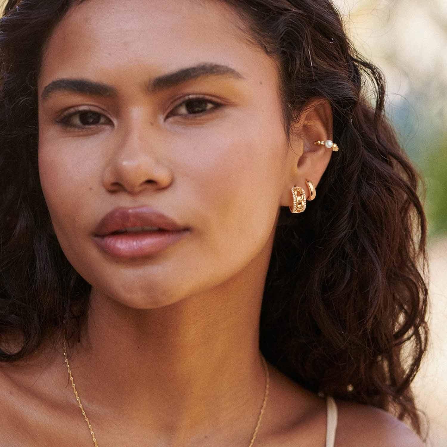 Close-up of a model wearing MYEARS® Link CZ Huggie Hoop Earrings, 14K gold plated, sparkling cubic zirconia, chic and modern earrings for women