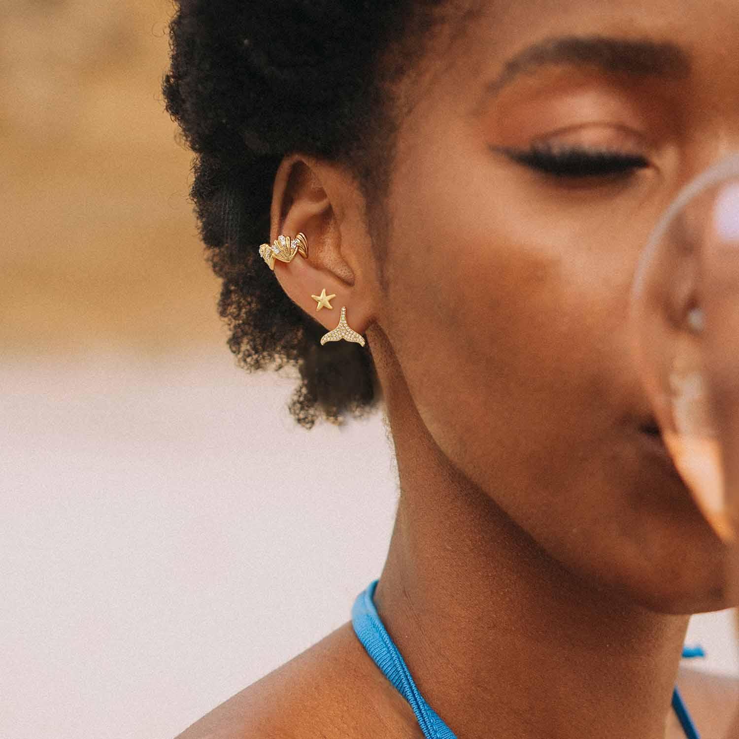 Close-up of a model wearing MYEARS® mermaid tail stud earrings, 14K gold finish, delicate ocean-inspired stud earrings for women.