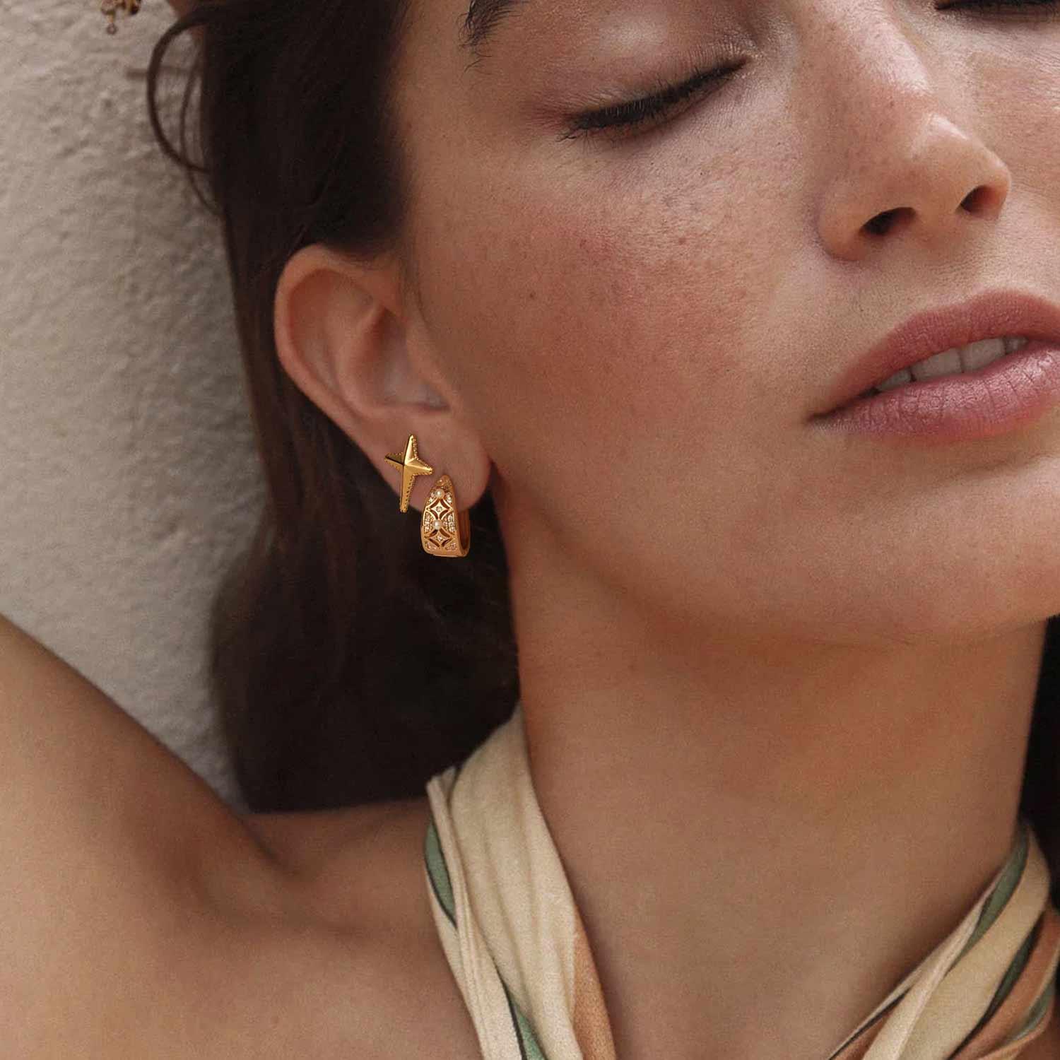 Close-up of a model wearing MYEARS® pearl huggie hoop earrings, 14K gold finish, stylish pearl hoop earrings for women.
