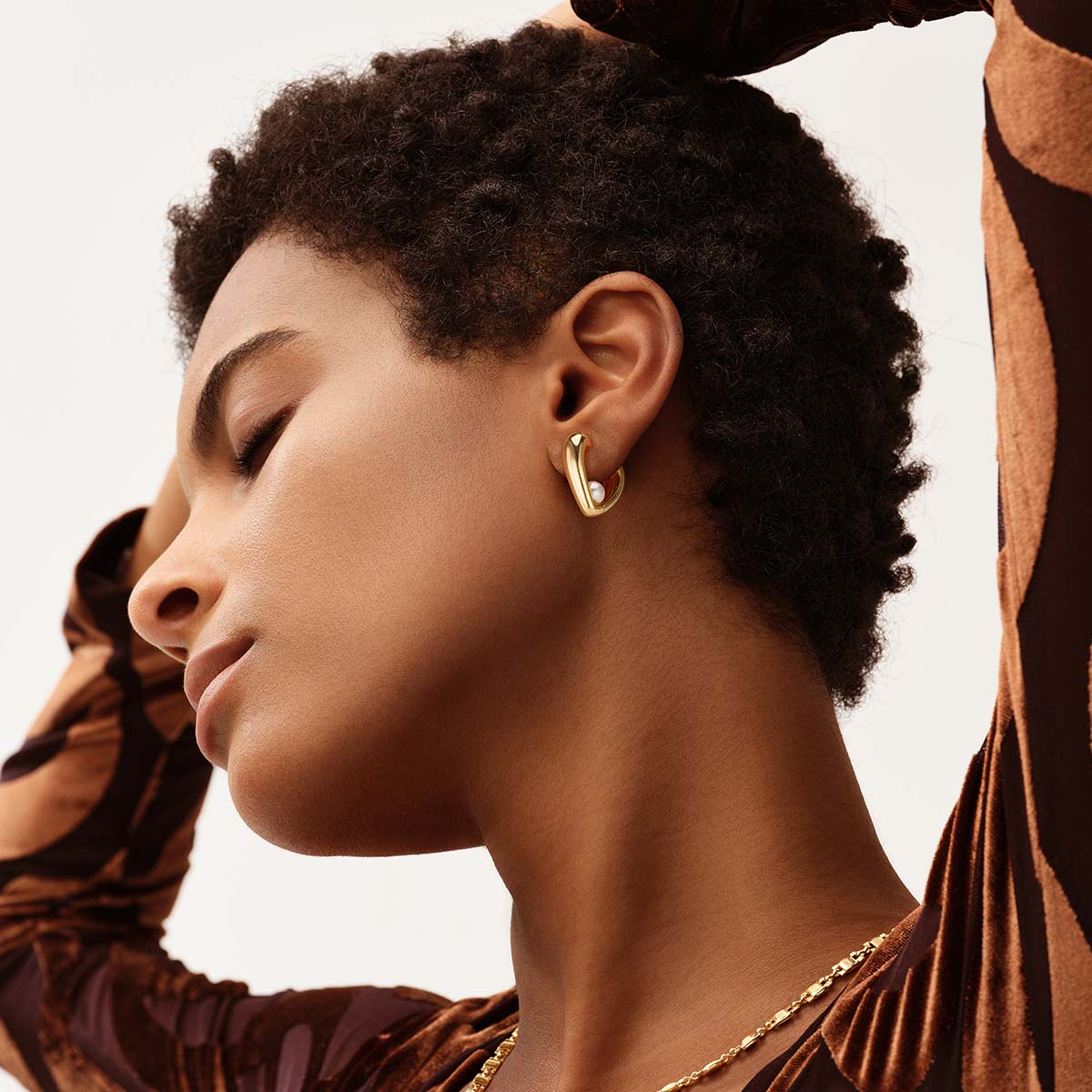 Close-up of a model wearing Myears® heart-shaped pearl earrings with 14K gold details, feminine pearl jewelry for women.