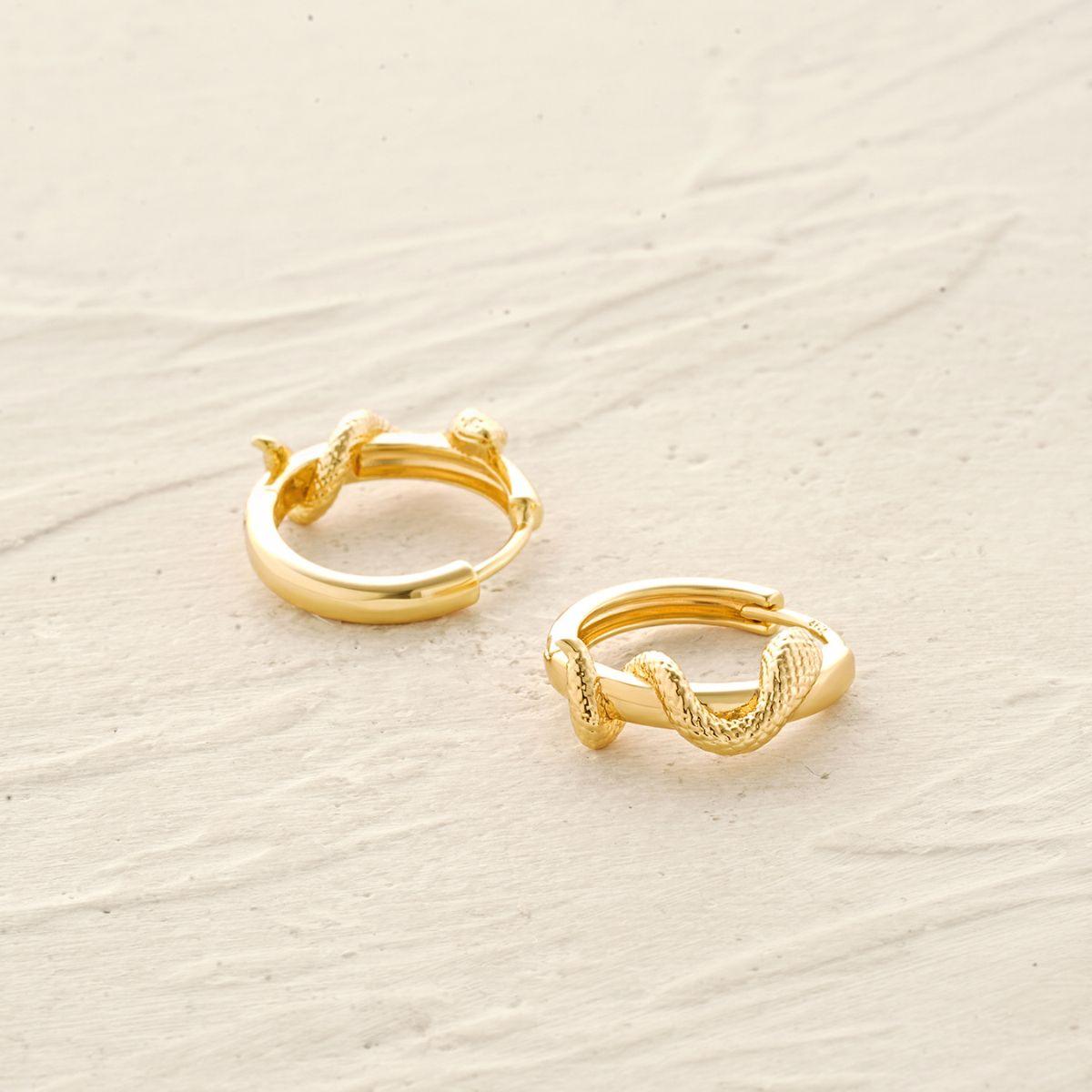 Detail of snake wrap huggie hoop earrings showing sculpted texture and polished finish