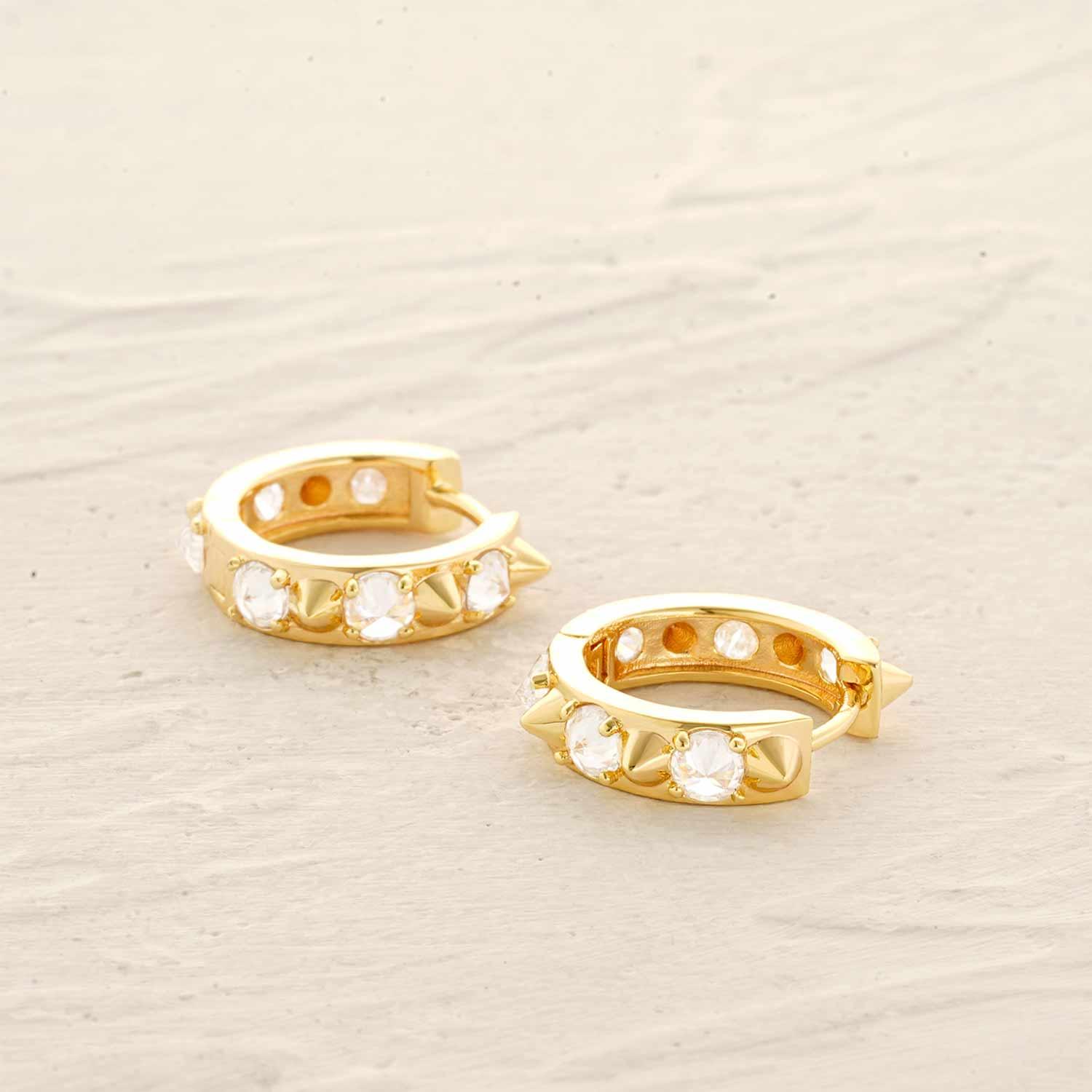 Close-up of spike CZ huggie hoop earrings showing gold finish and sparkling CZ stones