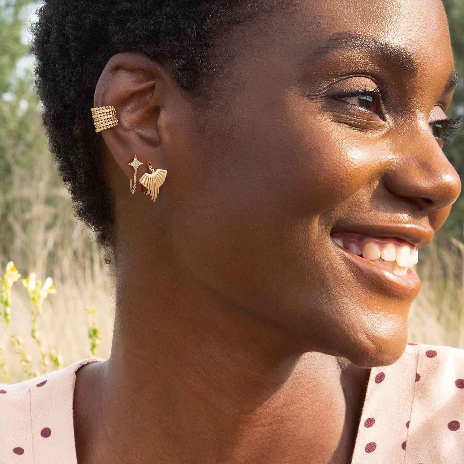 Side view of a woman wearing striking gold phoenix hoop earrings, showcasing the mythical bird design elegantly curving along the ear