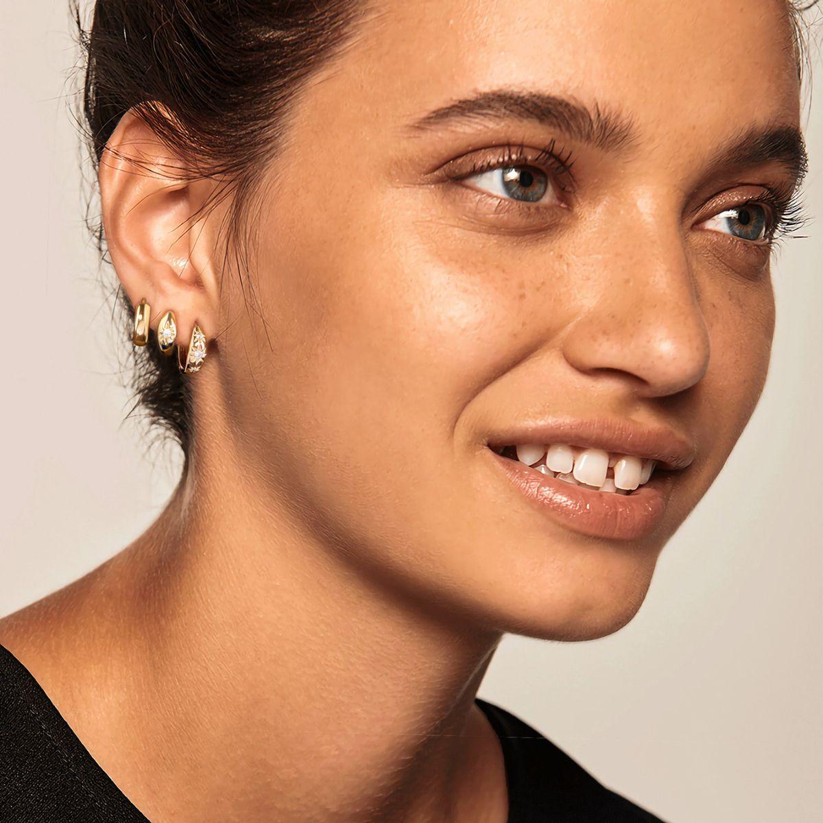 Close-up of MYEARS® Gold Triple Stars Huggie Earrings worn by model, delicate star huggie design