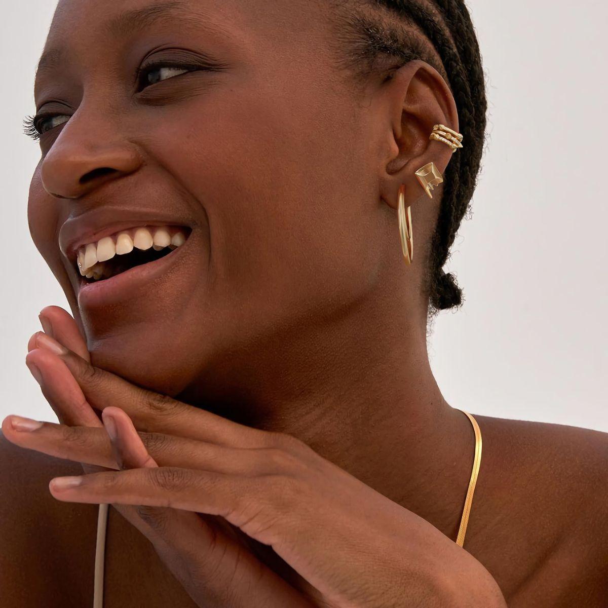 Close-up side view of a bold gold spike ear cuff elegantly wrapped around a woman‘s upper ear cartilage, showcasing its edgy-chic profile