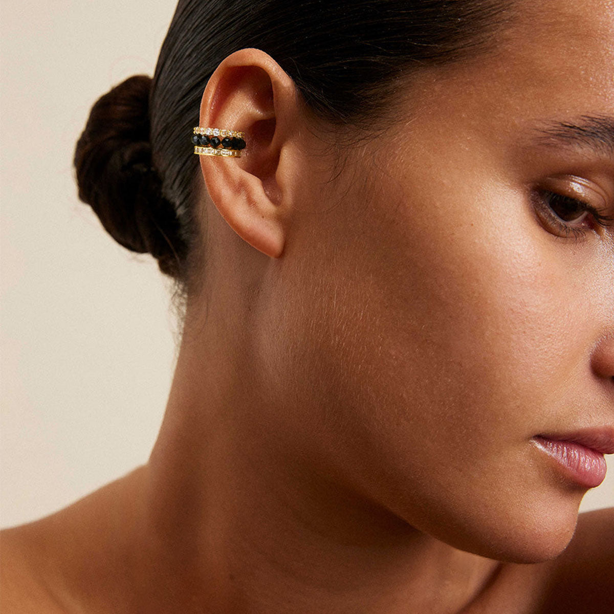 Close-up of MYEARS® black onyx ear cuff worn by a woman, gold non piercing ear cuff featuring a black onyx stone