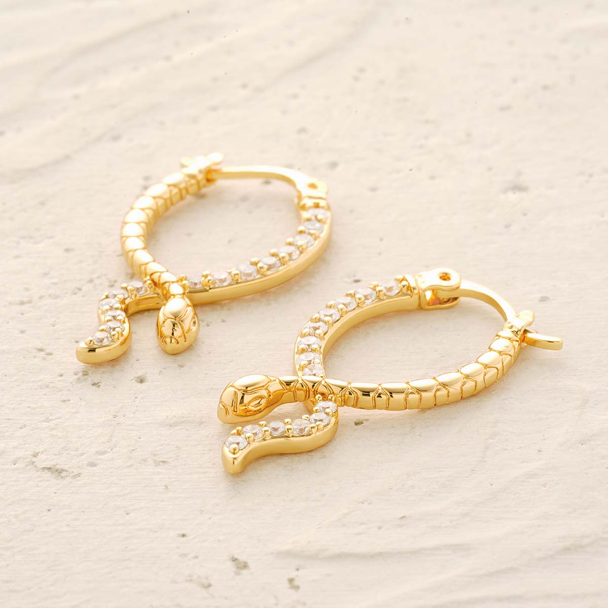 Detail scene of MYEARS® gold snake hoop earrings, focusing on the textured snake design, cubic zirconia accents
