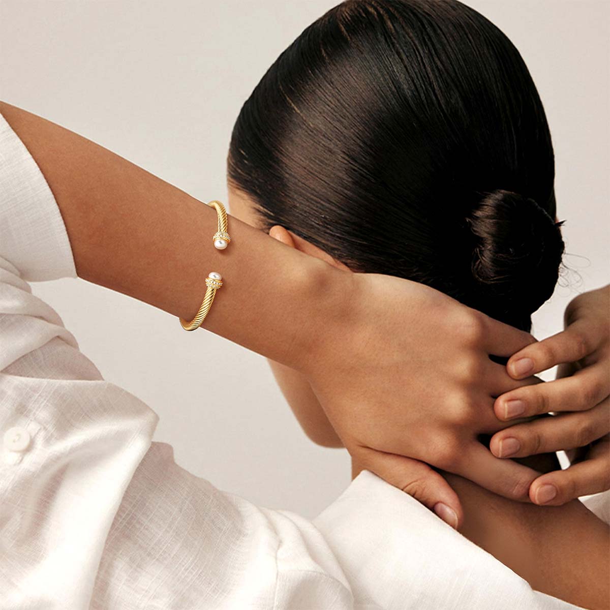 Close-up of a model wearing the Myears® gold twisted open cuff bracelet, 14K gold finish, modern minimalist women’s bracelet.