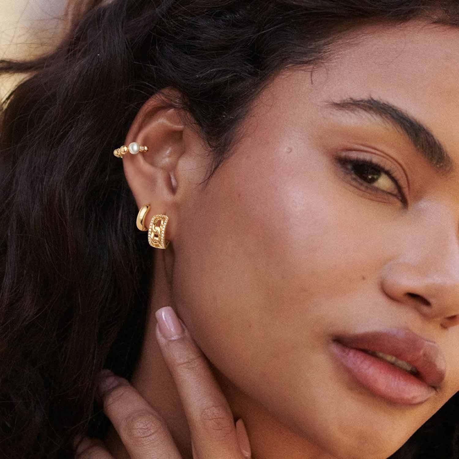 Model wearing MYEARS® Link CZ Huggie Hoop Earrings, 14K gold plated, sparkling cubic zirconia huggie hoops for women, elegant and versatile, perfect gift for her, suitable for everyday wear.