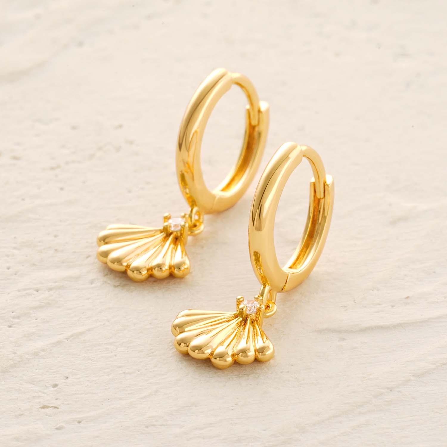 Close-up detail of the intricate clam shell texture and 14k gold plating on these dangle earrings, worn on the ear