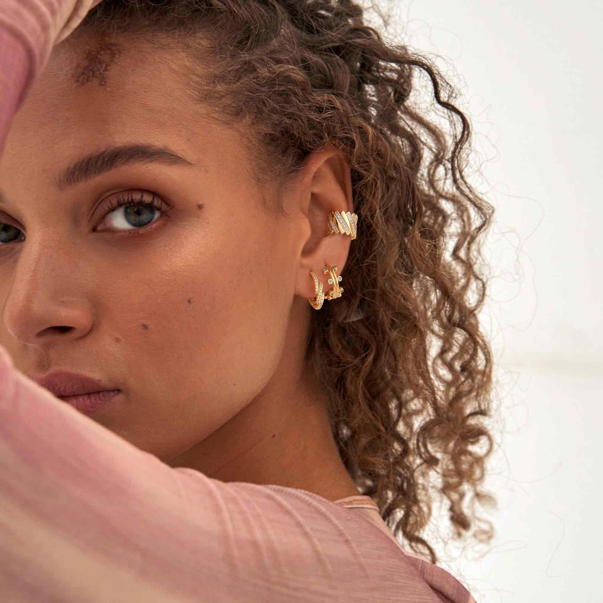 Close-up of MYEARS® turquoise hoop earrings worn by a woman, highlighting the gold hoops and turquoise detailing