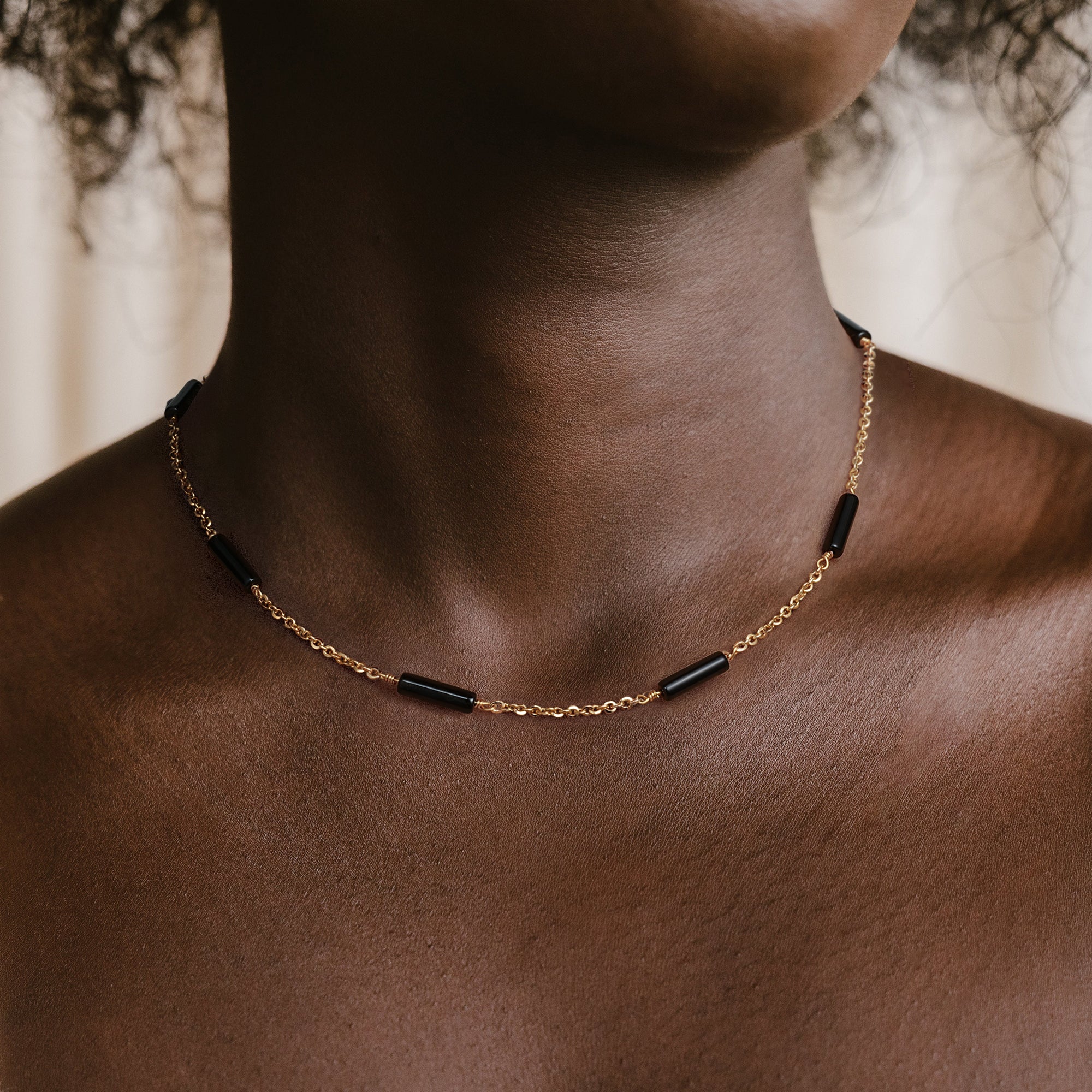 Model wearing the Myears® black onyx choker necklace in a natural daily outfit look